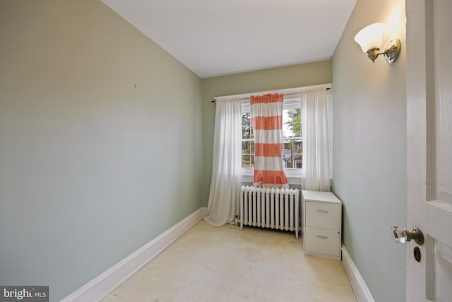 interior space featuring light carpet, radiator heating unit, and a crib