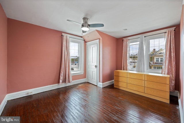 unfurnished bedroom featuring ceiling fan, dark hardwood / wood-style floors, and multiple windows