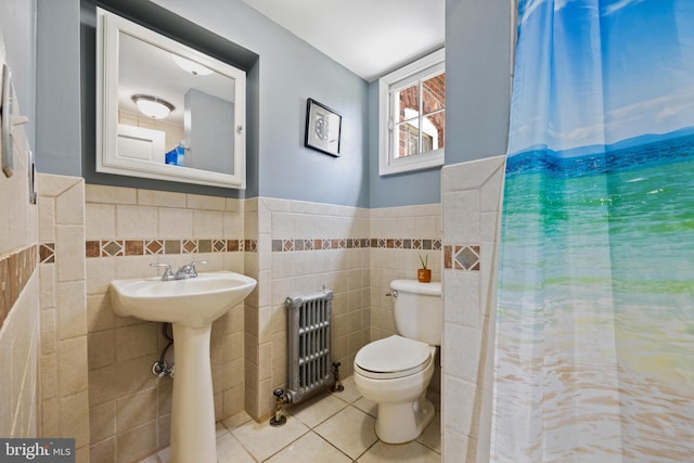 bathroom with toilet, radiator heating unit, tile patterned floors, and tile walls