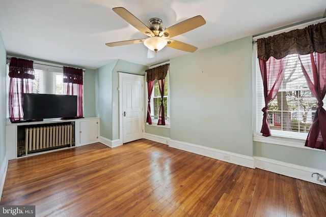 unfurnished living room with ceiling fan, radiator heating unit, and wood-type flooring