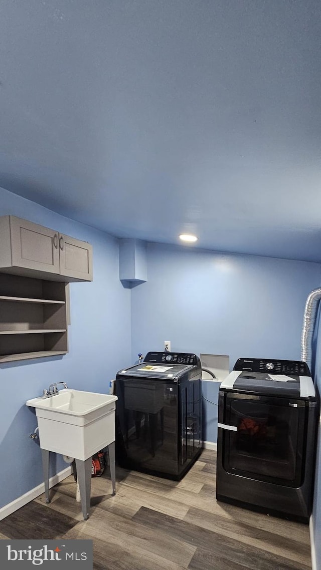 laundry room with separate washer and dryer, light hardwood / wood-style floors, and cabinets