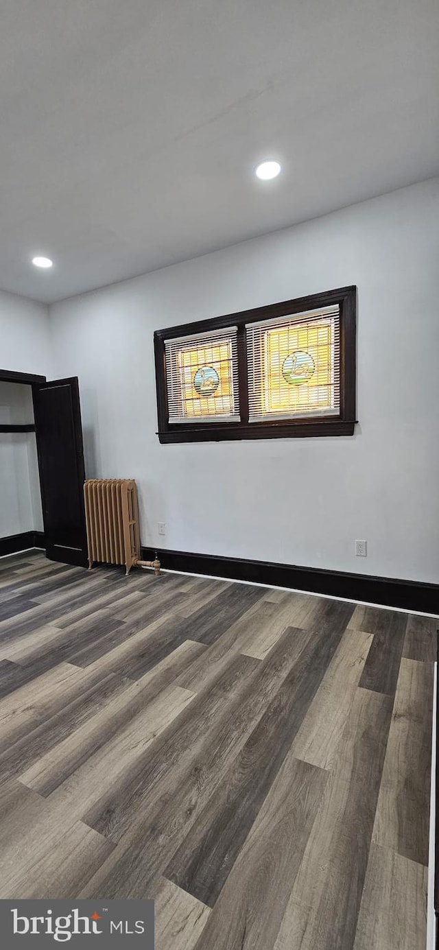 empty room featuring wood-type flooring and radiator heating unit