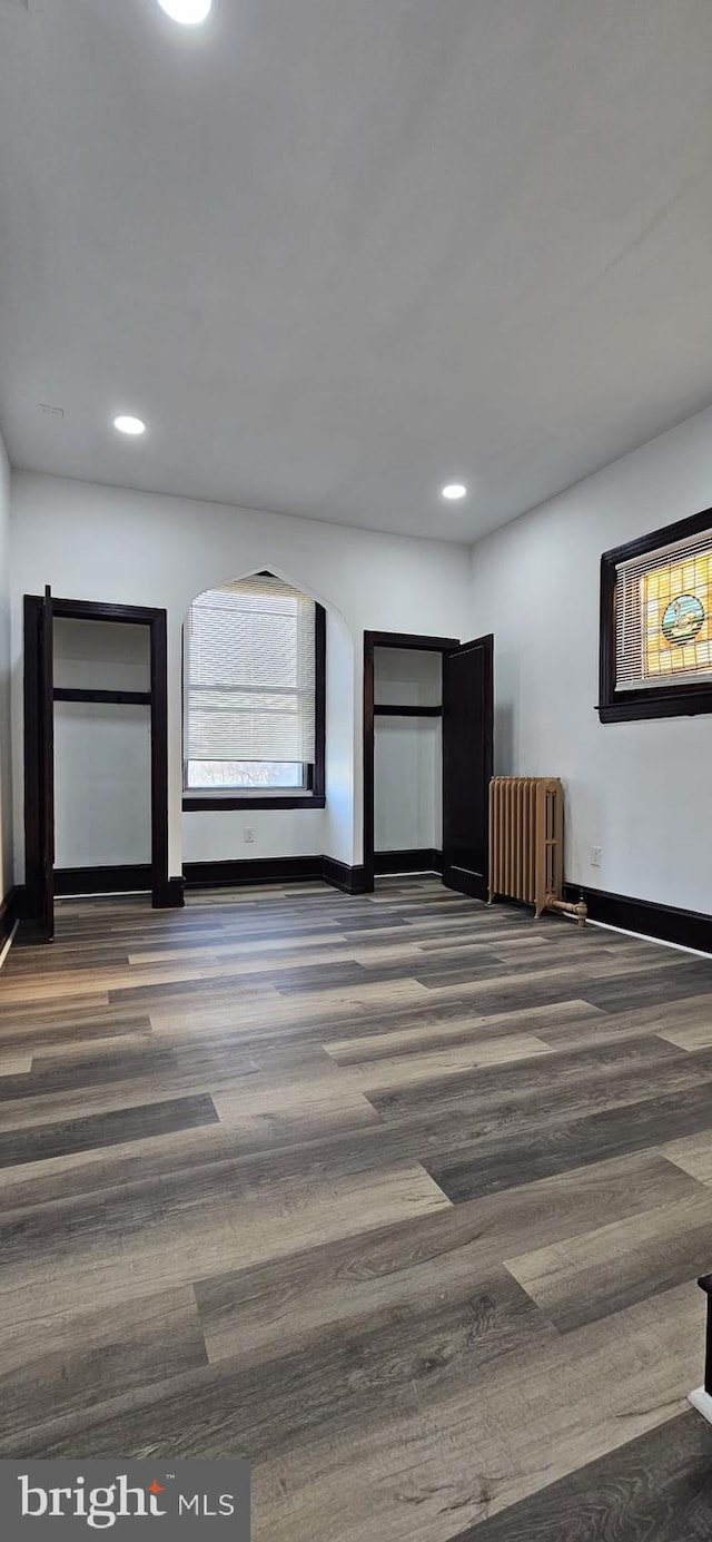 unfurnished room featuring dark hardwood / wood-style floors and radiator heating unit