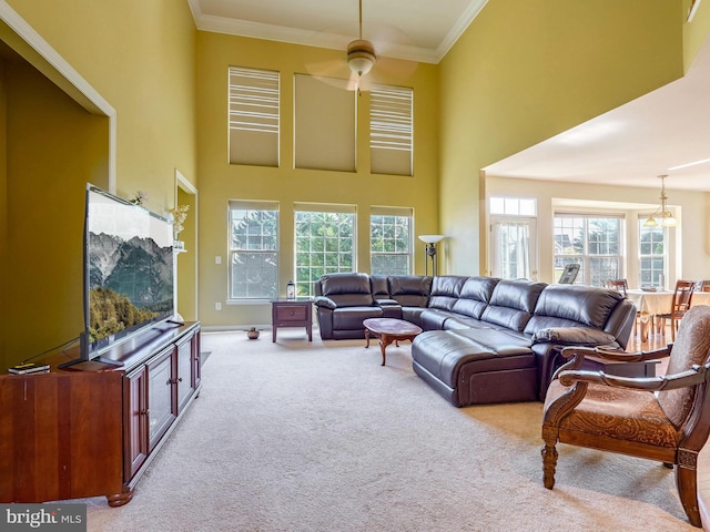 living room featuring ceiling fan, light carpet, a towering ceiling, and ornamental molding