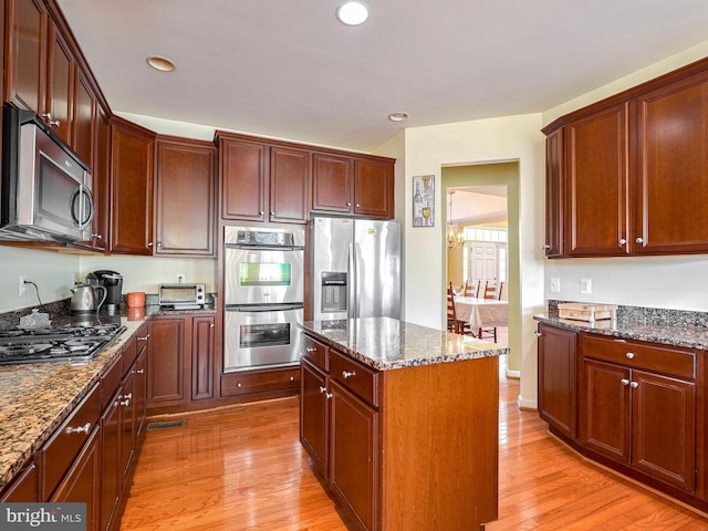 kitchen featuring a center island, dark stone countertops, light hardwood / wood-style floors, and appliances with stainless steel finishes