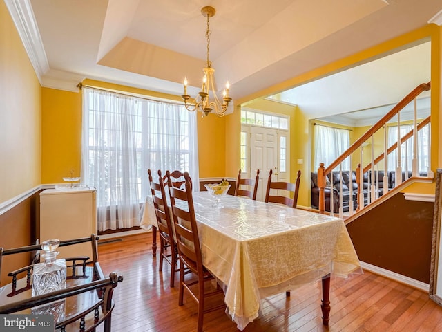 dining room featuring hardwood / wood-style flooring, plenty of natural light, crown molding, and an inviting chandelier