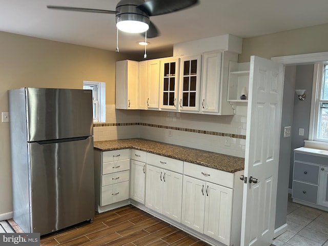 kitchen with white cabinets, stainless steel fridge, dark wood-type flooring, and dark stone counters