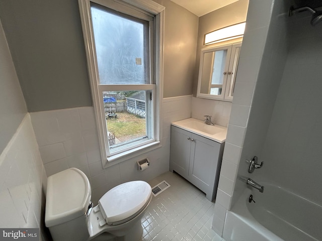 full bathroom featuring vanity, washtub / shower combination, tile patterned flooring, toilet, and tile walls