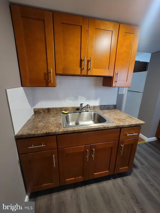 kitchen with dark hardwood / wood-style flooring, backsplash, dark stone countertops, and sink