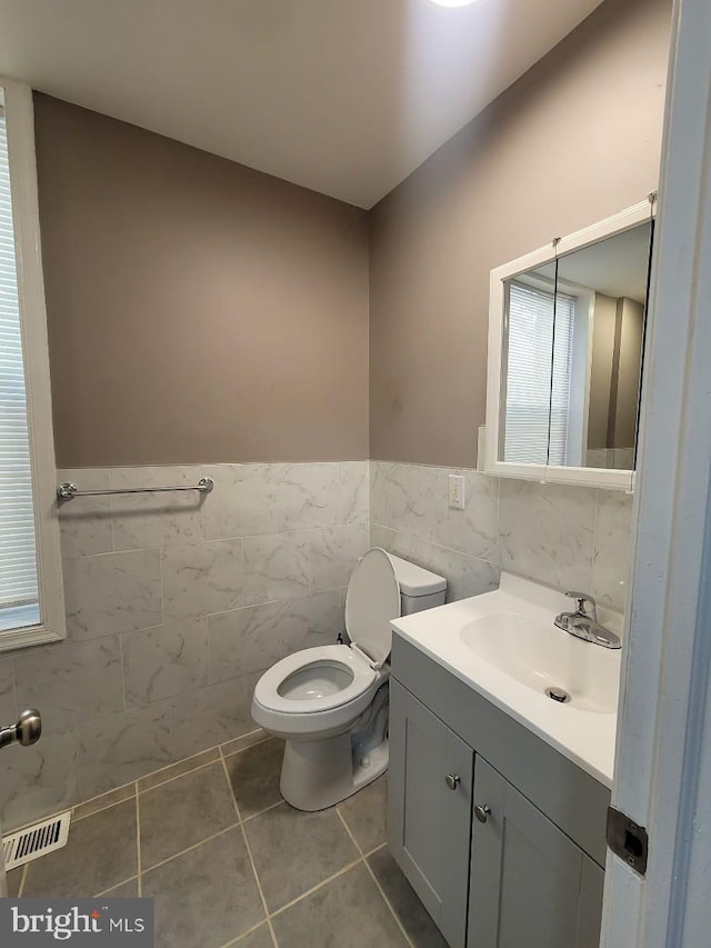 bathroom with tile patterned flooring, vanity, tile walls, and toilet