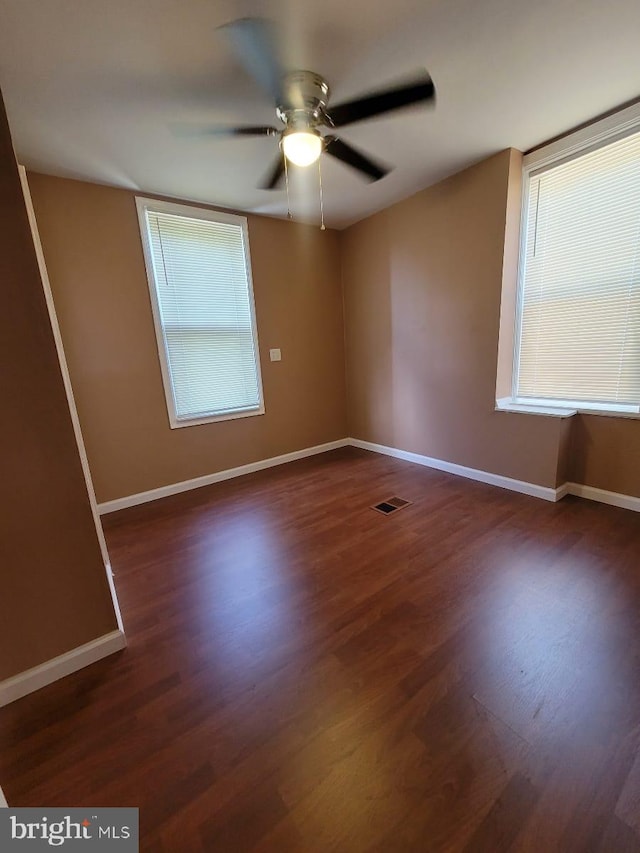 unfurnished room with ceiling fan and dark wood-type flooring