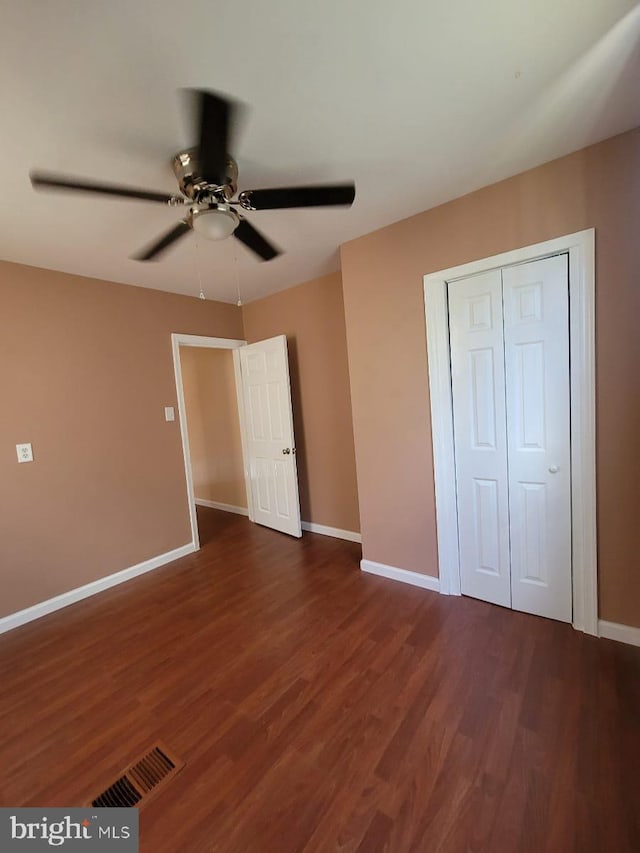 unfurnished bedroom featuring dark hardwood / wood-style floors, ceiling fan, and a closet