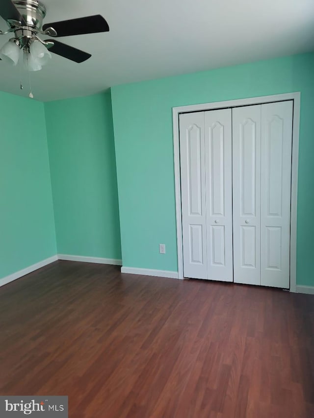 unfurnished bedroom with a closet, dark hardwood / wood-style floors, and ceiling fan