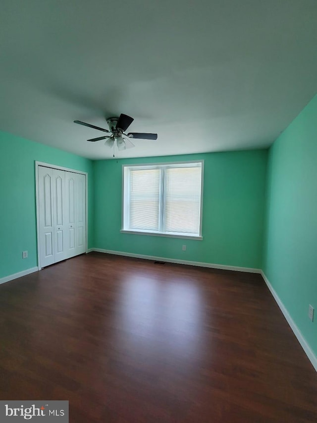 unfurnished bedroom featuring ceiling fan, dark hardwood / wood-style flooring, and a closet