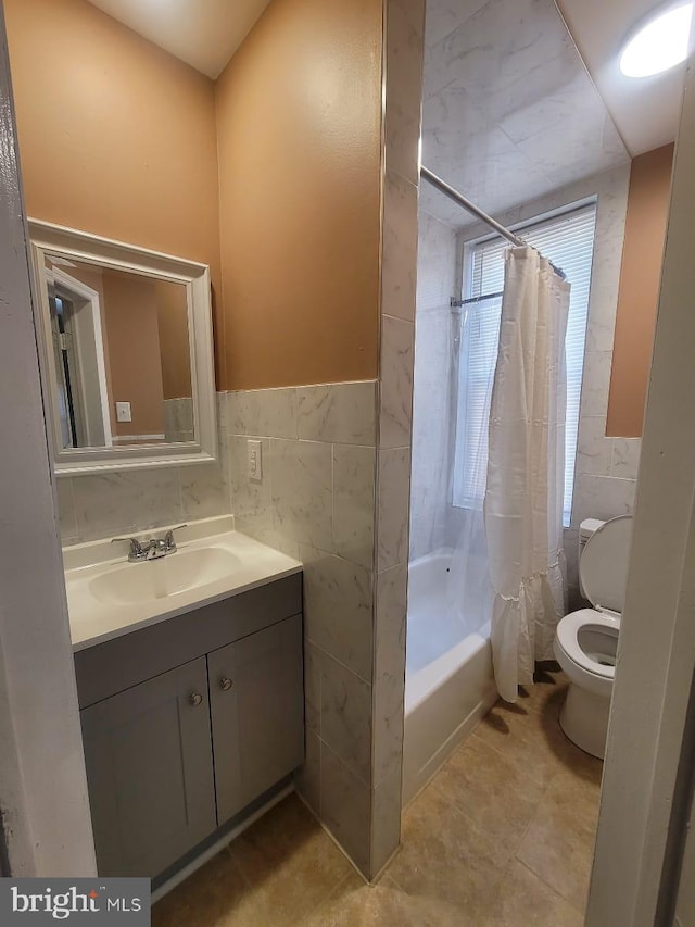 full bathroom with tile patterned floors, vanity, shower / bathtub combination with curtain, tile walls, and toilet