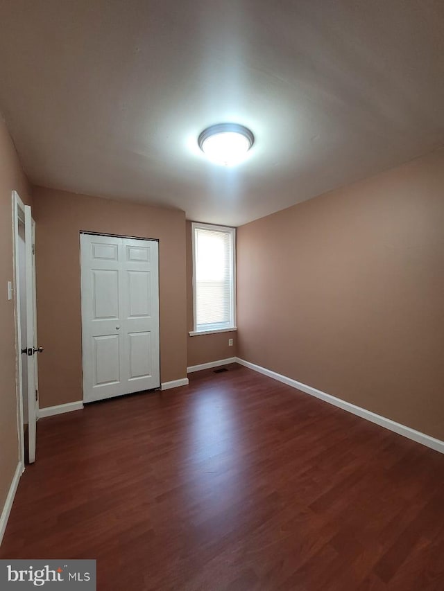 unfurnished bedroom featuring dark hardwood / wood-style flooring and a closet