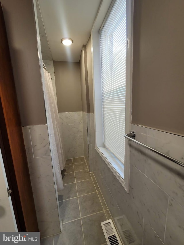 bathroom with tile patterned floors, tile walls, and a shower with shower curtain