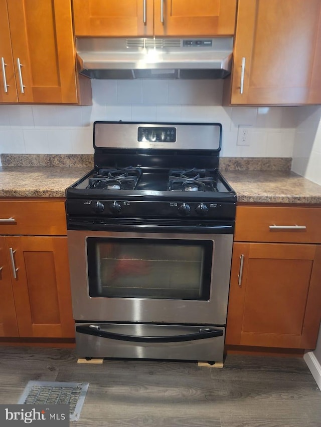 kitchen featuring gas stove, decorative backsplash, and dark wood-type flooring