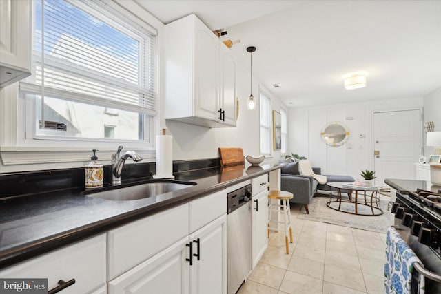 kitchen with sink, light tile patterned floors, pendant lighting, white cabinets, and appliances with stainless steel finishes