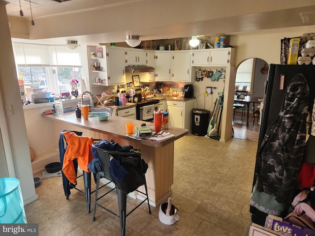 kitchen with kitchen peninsula, white cabinets, stainless steel electric stove, and sink