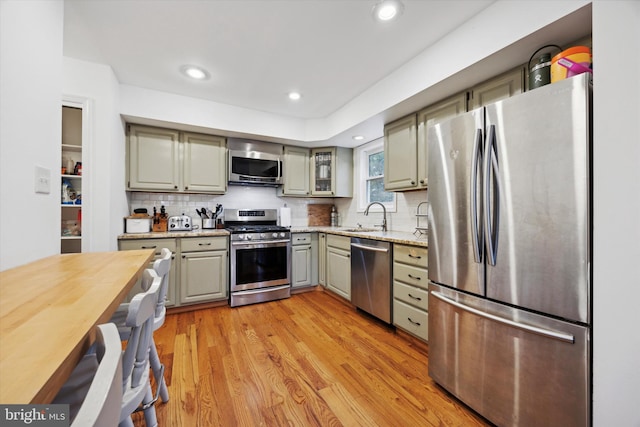 kitchen featuring backsplash, stainless steel appliances, light hardwood / wood-style floors, and sink