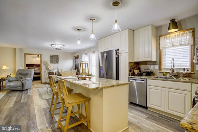 kitchen with decorative backsplash, white cabinetry, stainless steel appliances, and light stone counters