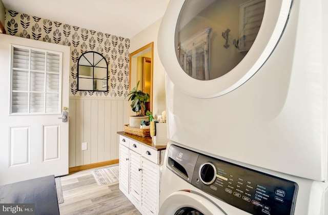 clothes washing area featuring stacked washing maching and dryer and light hardwood / wood-style flooring