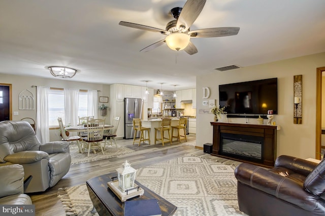 living room with ceiling fan and light hardwood / wood-style floors