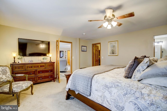 bedroom featuring ceiling fan, light colored carpet, and connected bathroom