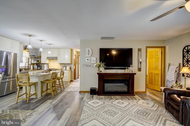living room featuring light hardwood / wood-style floors, ceiling fan, and sink