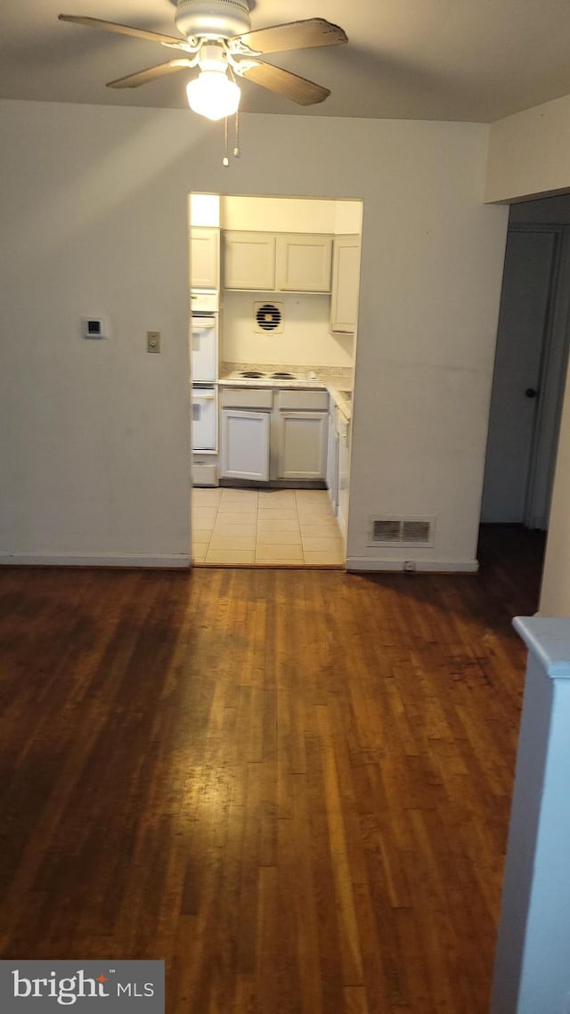 kitchen with white double oven, white cabinets, light hardwood / wood-style flooring, ceiling fan, and cooktop