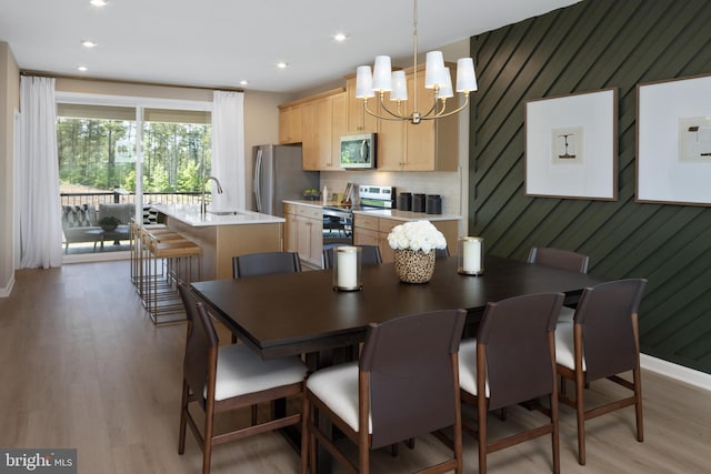 dining room featuring sink, light hardwood / wood-style flooring, and an inviting chandelier