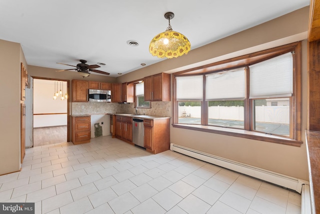 kitchen featuring appliances with stainless steel finishes, backsplash, ceiling fan, a baseboard radiator, and hanging light fixtures