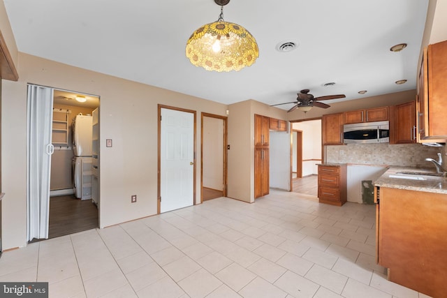 kitchen featuring decorative backsplash, ceiling fan, sink, light tile patterned floors, and hanging light fixtures