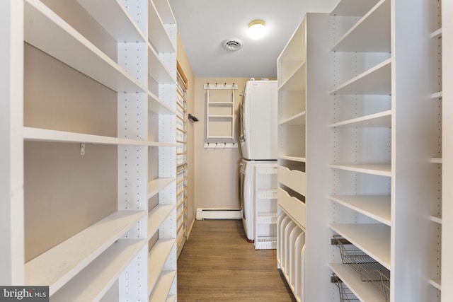 walk in closet featuring wood-type flooring, stacked washer / dryer, and a baseboard radiator