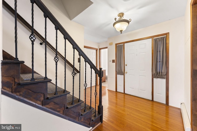 foyer entrance featuring wood-type flooring and a baseboard radiator