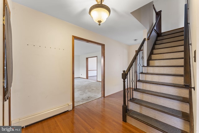 stairway featuring a baseboard radiator and hardwood / wood-style flooring