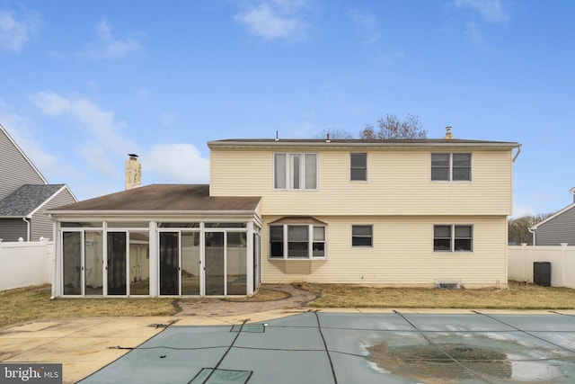 rear view of property with a sunroom, a patio, and a covered pool