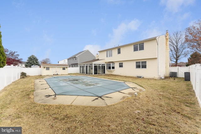 view of swimming pool featuring a yard, central air condition unit, a patio area, and a sunroom