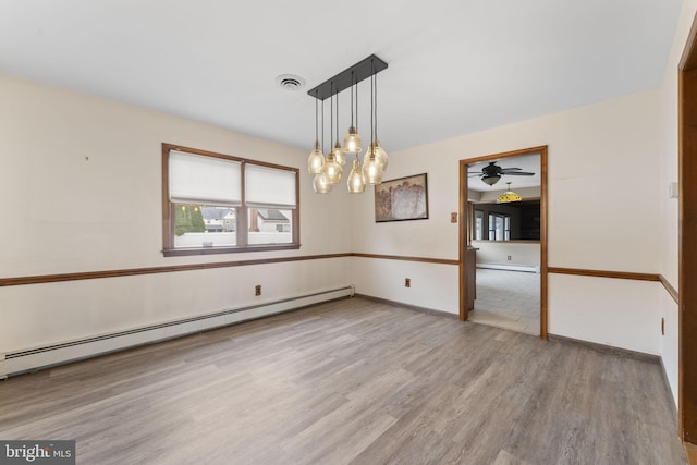 unfurnished dining area with baseboard heating, ceiling fan, and wood-type flooring