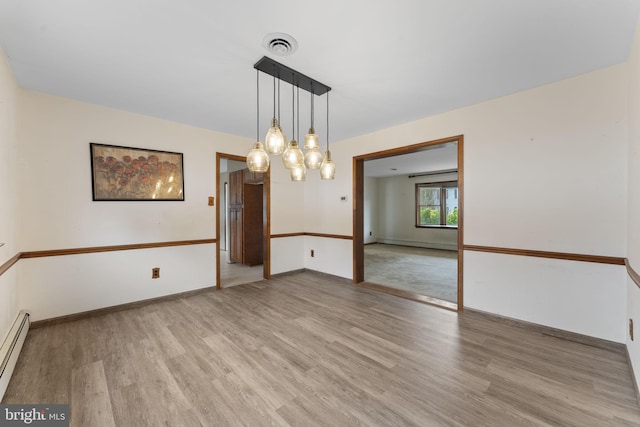 unfurnished dining area with light hardwood / wood-style floors and a baseboard heating unit