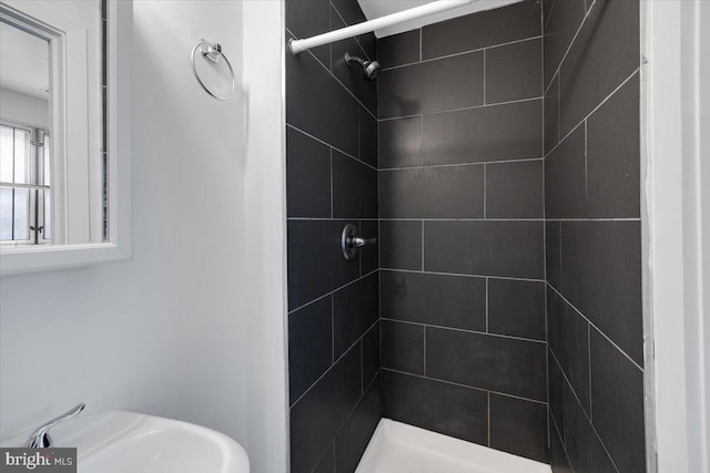 bathroom featuring a tile shower and sink