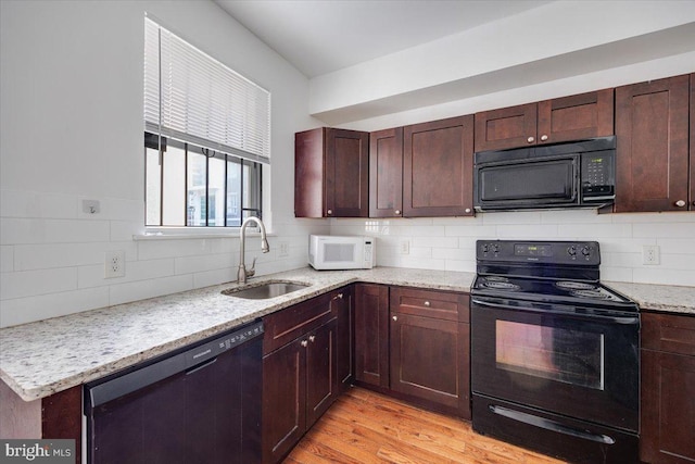 kitchen featuring light stone countertops, backsplash, sink, black appliances, and light hardwood / wood-style flooring