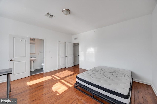 bedroom with hardwood / wood-style flooring and ensuite bathroom