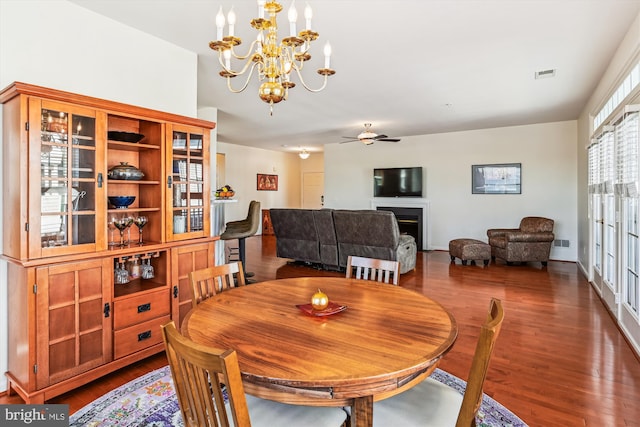 dining space with ceiling fan with notable chandelier and dark hardwood / wood-style floors