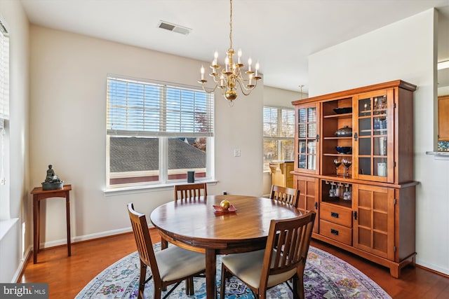 dining room featuring a wealth of natural light, dark hardwood / wood-style floors, and an inviting chandelier