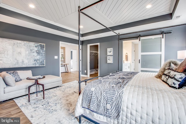 bedroom featuring a walk in closet, wood ceiling, a barn door, hardwood / wood-style floors, and a closet