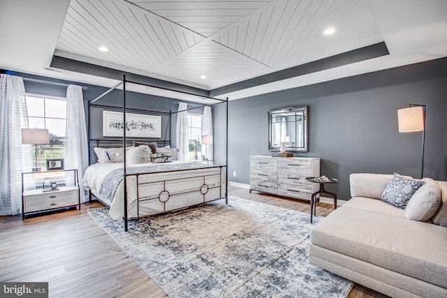 bedroom with hardwood / wood-style floors, a raised ceiling, and wood ceiling