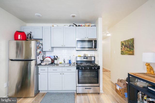 kitchen featuring backsplash, light stone counters, stainless steel appliances, and light hardwood / wood-style floors