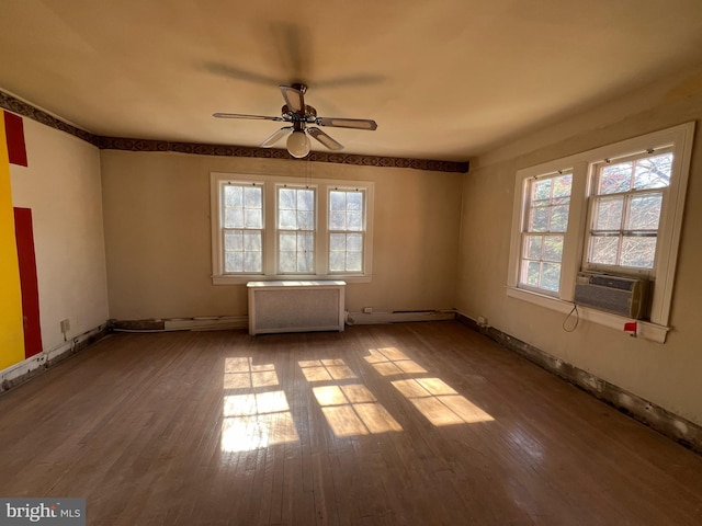 unfurnished room featuring hardwood / wood-style flooring, a baseboard radiator, cooling unit, and a healthy amount of sunlight